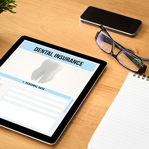 Dental insurance form on tablet next to notepad