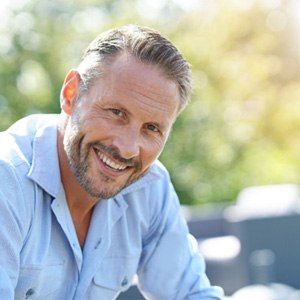 Older bearded man sitting outside and smiling