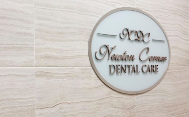 Newton Corner Dental Care sign on a wood wall