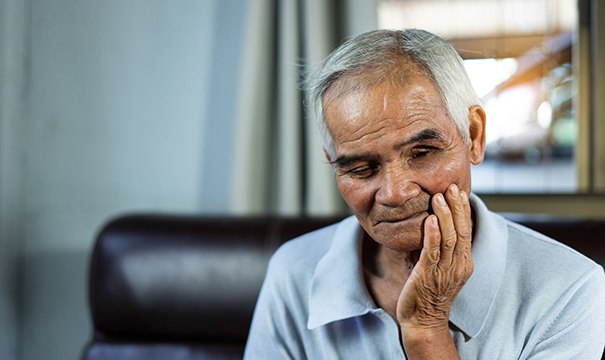 Man sitting on couch touching face looking concerned