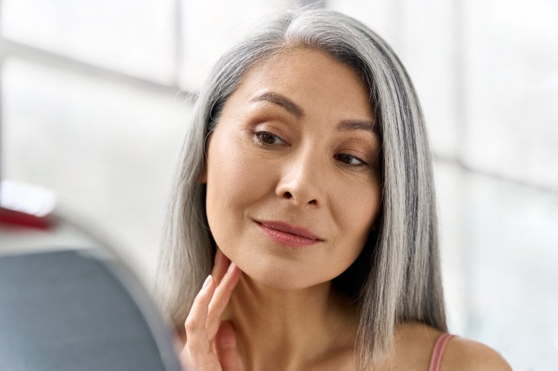 Patient smiling in the mirror after cosmetic dentistry